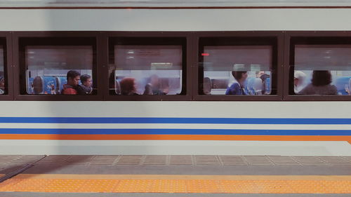 People at railroad station platform seen through train window