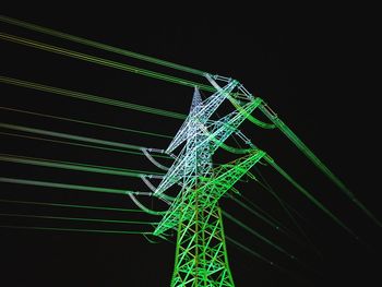 Low angle view of illuminated lighting equipment against black background