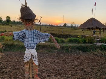 Scarecrow at farm against sky during sunset