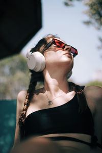 Portrait of young woman drinking water against sky