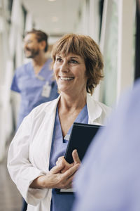 Happy female doctor looking away while standing in hospital