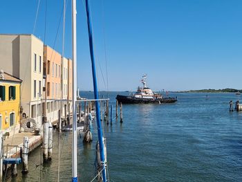 Sailboats in sea by buildings against clear sky