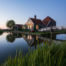 Houses by calm lake against clear sky