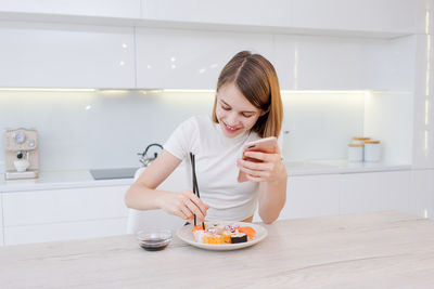 Portrait of young woman drinking water at home