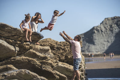 People standing on rock against sky