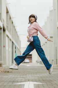 Full length of woman jumping against wall