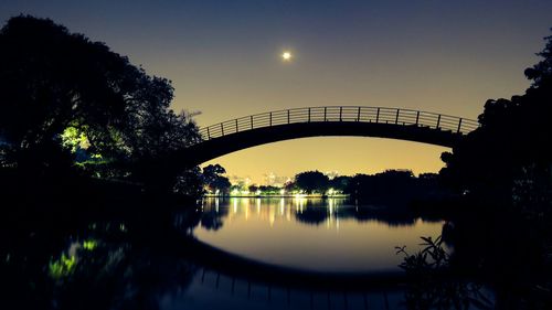 Silhouette bridge over river against sky during sunset