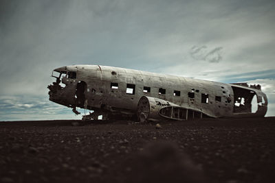 Damaged airplane on beach against sky