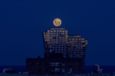 Low angle view of buildings against blue sky at night