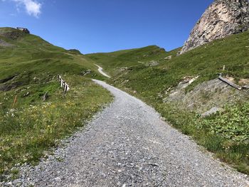 Road amidst grass and mountains against sky