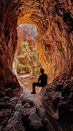 Rear view of man sitting on rock