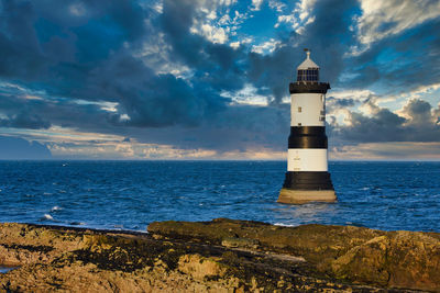 Lighthouse amidst sea and buildings against sky