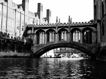 Bridge over river by buildings against clear sky