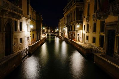 Canal amidst buildings in city at night