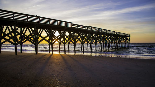 Pier over sea against sky during sunset