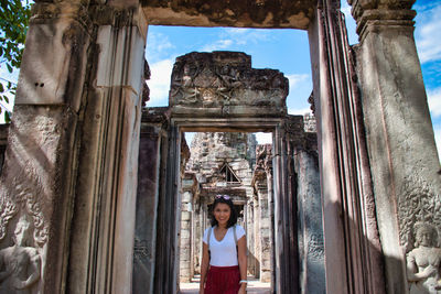Portrait of young woman standing at historical building