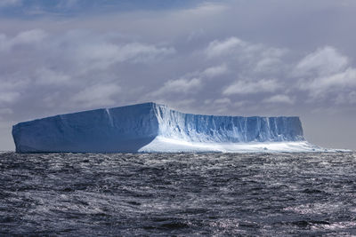 Glacier in sea against sky