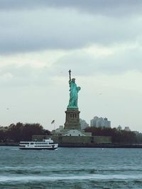 Statue in sea against cloudy sky