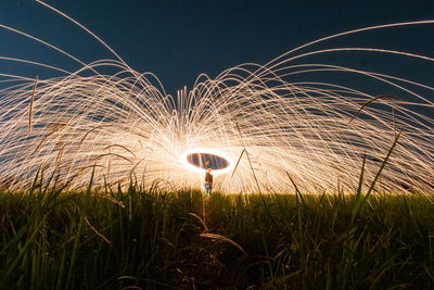 Light trails on field against sky at night