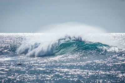 Scenic view of sea waves splashing against clear sky