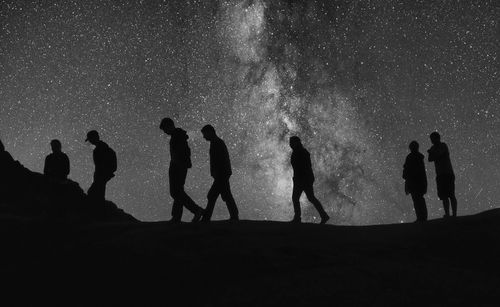 Silhouette people against sky at night