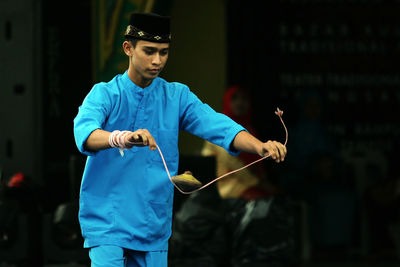 Young man playing with spinning top on rope outdoors