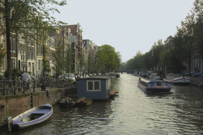 Boats moored on river in city against clear sky