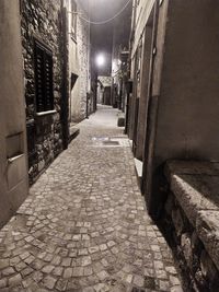 Narrow alley amidst buildings in city at night