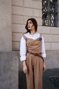 Portrait of young woman standing against wall