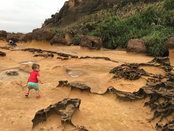 Rear view of boy walking on sand