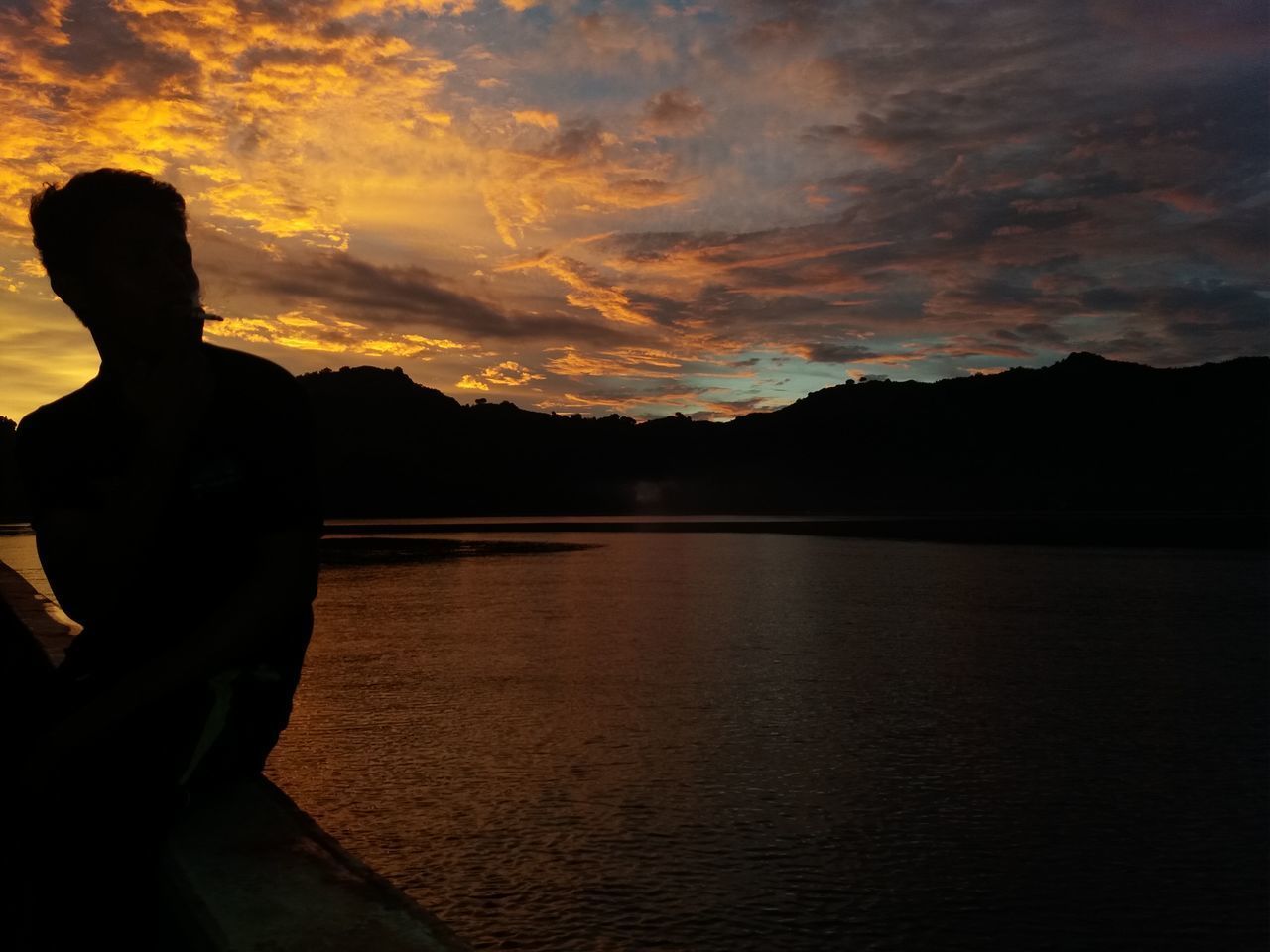 SILHOUETTE WOMAN STANDING BY LAKE AGAINST SKY DURING SUNSET