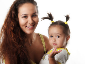 Portrait of happy mother holding baby girl against white background