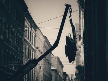 Low angle view of silhouette rope hanging on street against buildings