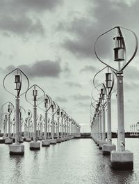 Street lights on pier by river against sky