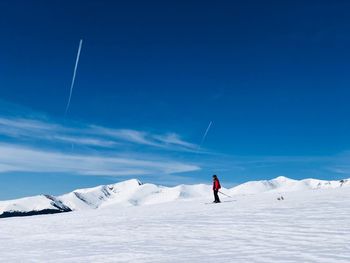 Woman skiing on snow covered land against sky