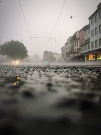 Wet road by railroad tracks in city against clear sky