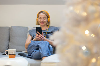 Young man using smart phone while sitting on laptop