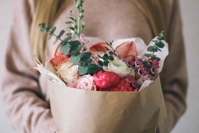 Midsection of woman with bouquet of flowers