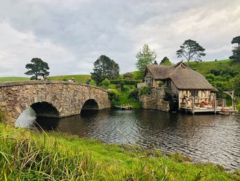 Arch bridge over river by building against sky