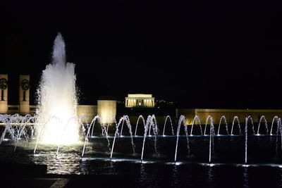 Illuminated fountain against sky at night