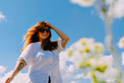 Portrait of young woman standing against sky