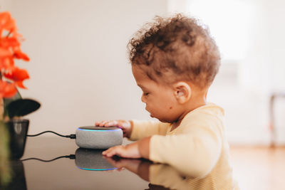 Cute baby touching smart speaker at home