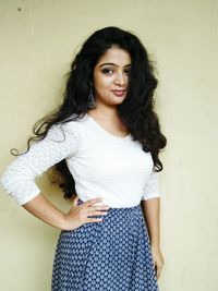 Portrait of smiling young woman standing against wall