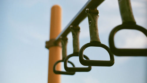 Low angle view of metallic handle against sky