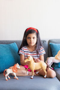 Portrait of cute girl sitting on sofa with dog at home