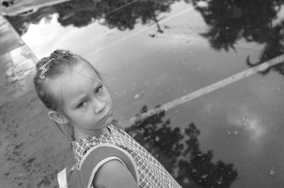 High angle portrait of sad schoolgirl standing by puddle