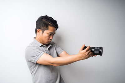 Midsection of man photographing against white background