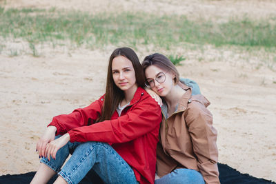 Two young caucasian young women friends sitting on the sand at the beach