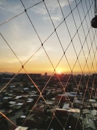 Chainlink fence against sky during sunset