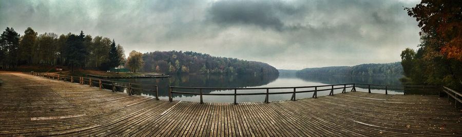 Panoramic shot of pier at calm lake against cloudy sky